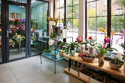 A bustling flower shop filled with a vibrant assortment of plants and flowers, creating a colorful and fragrant atmosphere.