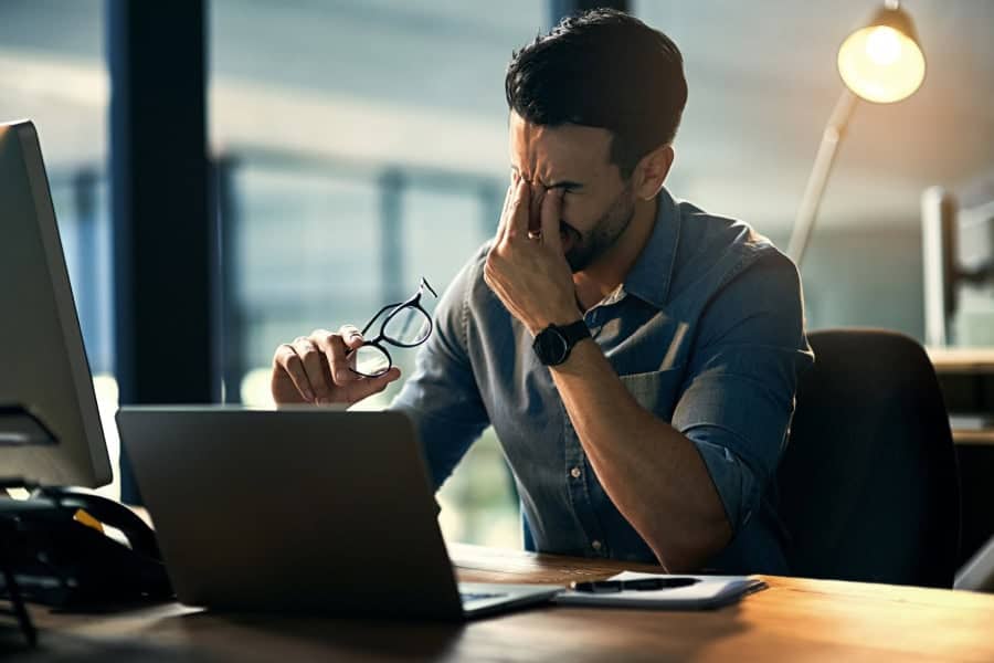 A man stressed while working late at night, needing support from Columbus IT management.