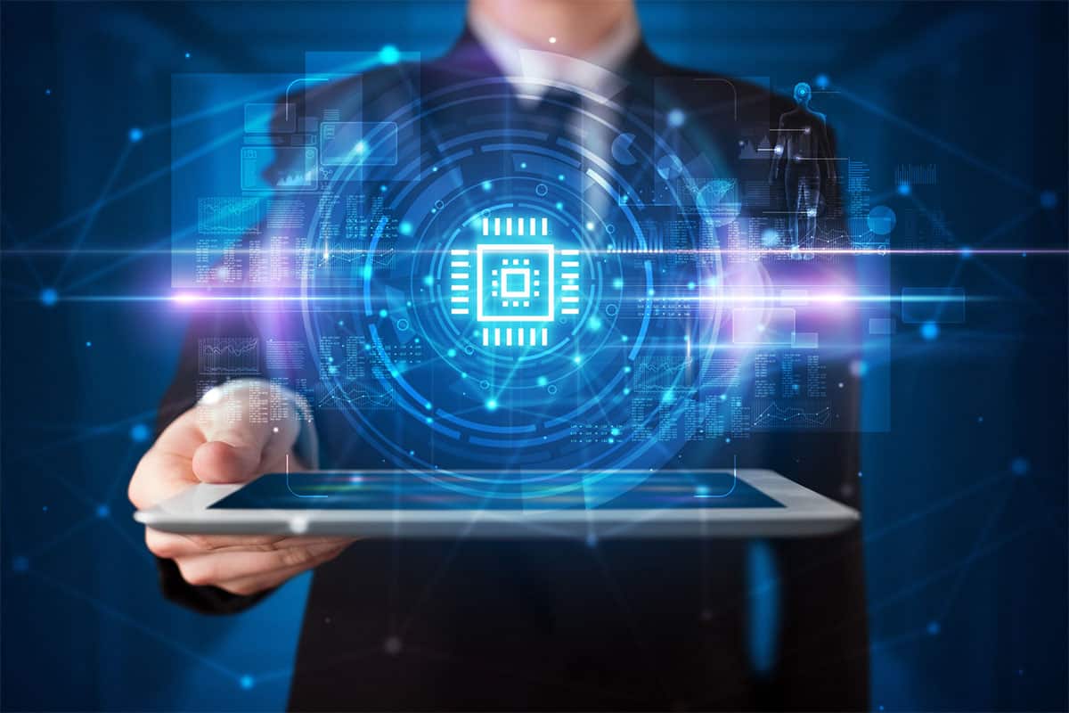 A businessman is holding a tablet with an illustration of a computer chip emerging from the tablet.