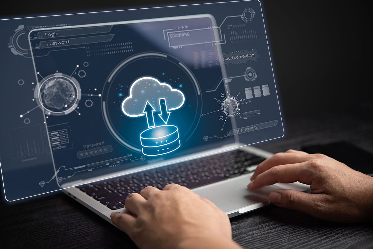 A person is using a laptop showing a graphic of a server uploading data to a cloud.