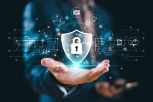 A businessman is holding out his hand to reveal a cyber shield graphic with a padlock.